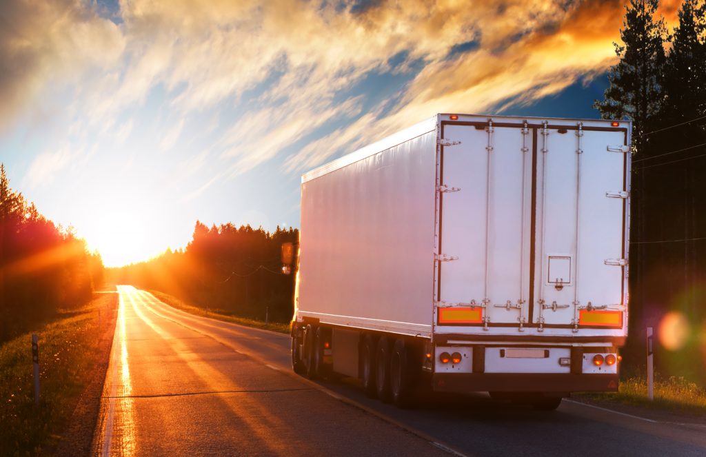 white 18 wheeler on the road at sunset