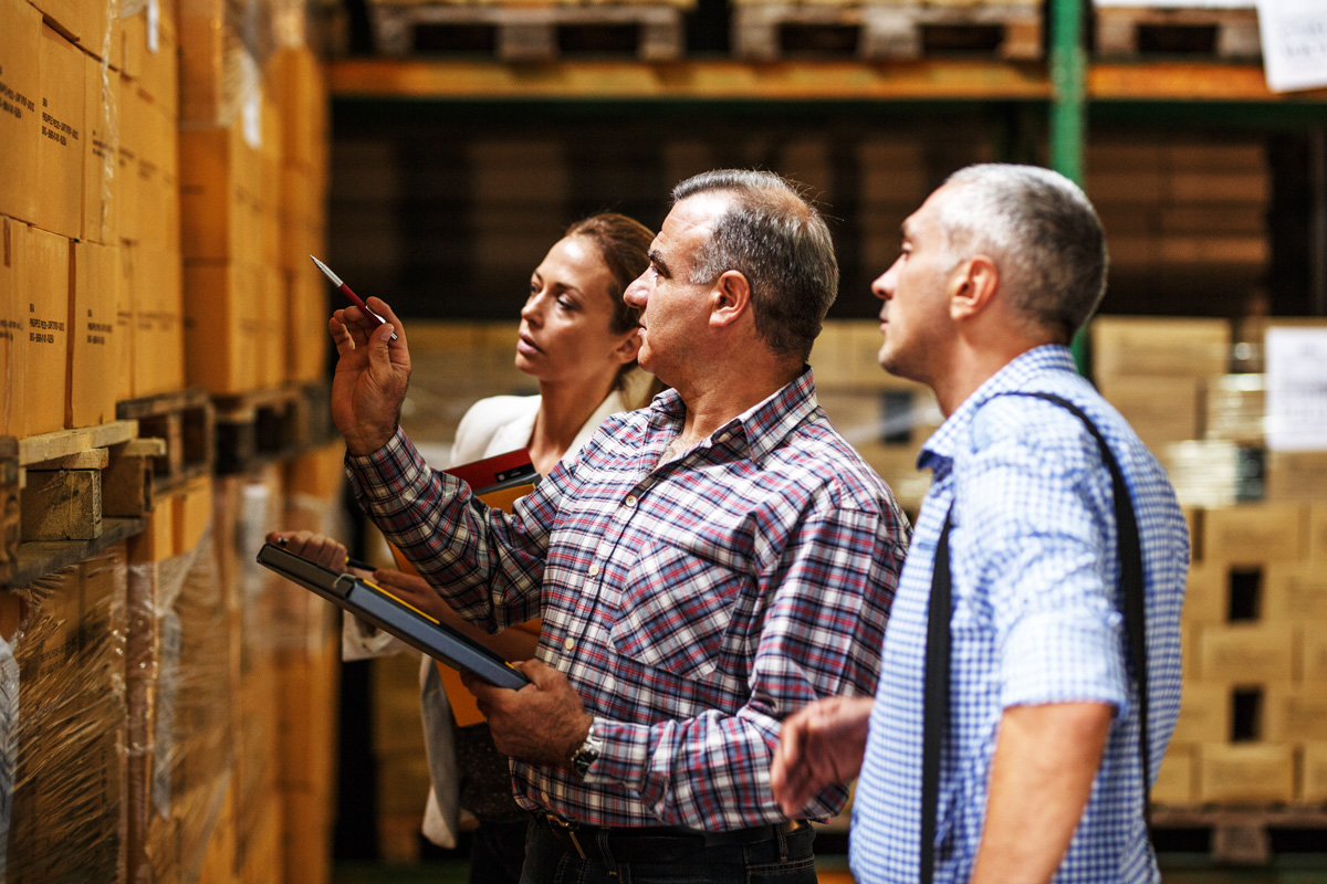 Three people reviewing inventory at a customs warehouse in El Paso.
