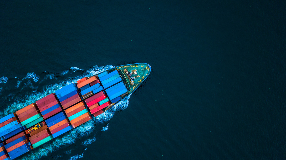 An aerial view of a shipping boat carrying freight in the ocean.